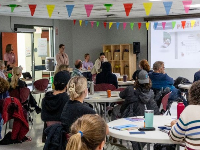 people seated at tables in a large room in a workshop setting