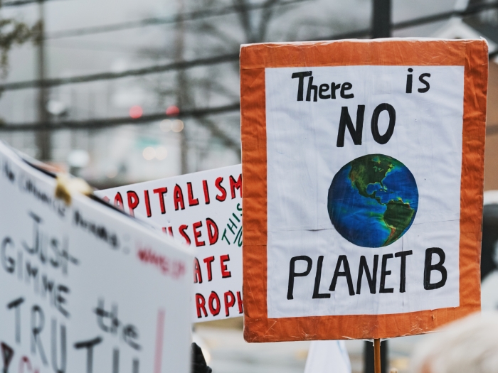 A sign saying "The is NO planet B" is being held at a rally.